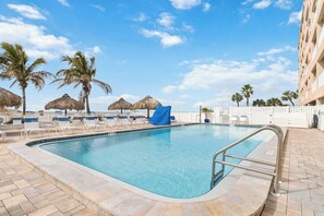 Ein Swimmingpool mit Liegestühlen und Palmen.