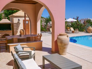 A poolside area with lounge chairs, a table, and a large vase.