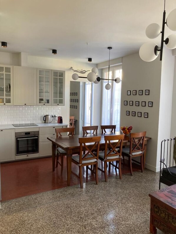 A modern kitchen with white cabinets, a central island, and a dining area with wooden chairs and a table.