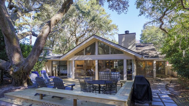 A modern house with a large deck, outdoor seating, and a covered barbecue area. - 12 Dewberry: Elegant Greenwood Forest Home, Sleeps 8,Free Bikes, Pool, Tennis (Hilton Head Island)