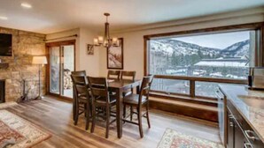 A dining area with a large window overlooking a snowy landscape. - Heart of Lionshead + Free Parking - Rooftop Hot Tub (Vail)