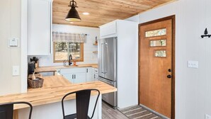 Une cuisine moderne avec des armoires blanches, un plan de travail en bois et un réfrigérateur en acier inoxydable.