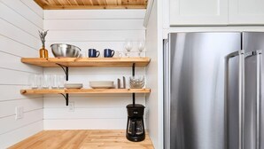 Une cuisine avec des étagères en bois, une machine à café et un réfrigérateur en acier inoxydable.