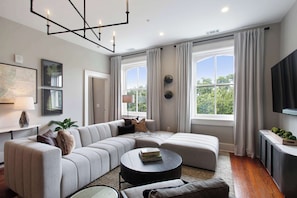 A modern living room with a sectional sofa, a round coffee table, and a flat-screen TV.