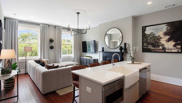A modern living room with a sofa, dining area, and kitchen island. - Restored 1800's Condo | Downtown Savannah (Savannah)