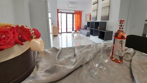 Un salon avec un canapé, une table basse et un vase décoratif rempli de fleurs. On peut voir deux verres à vin et une bouteille sur la table.