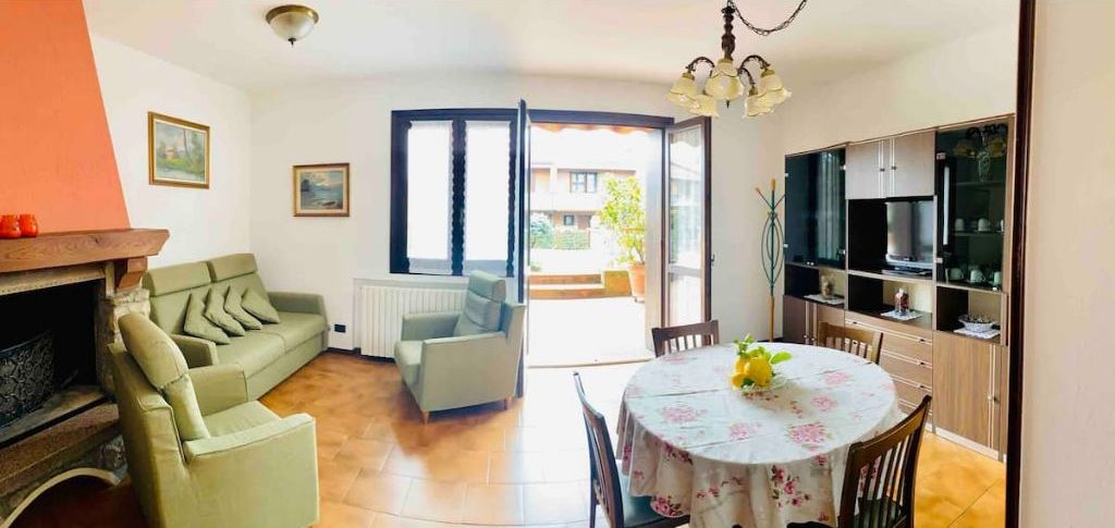 Un salon avec un canapé, une table à manger avec des chaises, un coin cuisine avec des placards et une grande fenêtre.