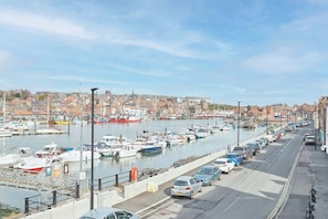 A marina with boats docked, a road alongside, and buildings in the background. - Host & Stay | Coastal Townhouse (Whitby)