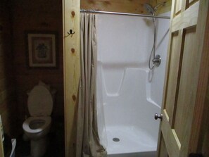 A wooden-framed bathroom with a white bathtub, a shower, and a toilet. - A cozy new cabin in rural setting with a hot tub on porch. Beautiful rural view. (Albany)