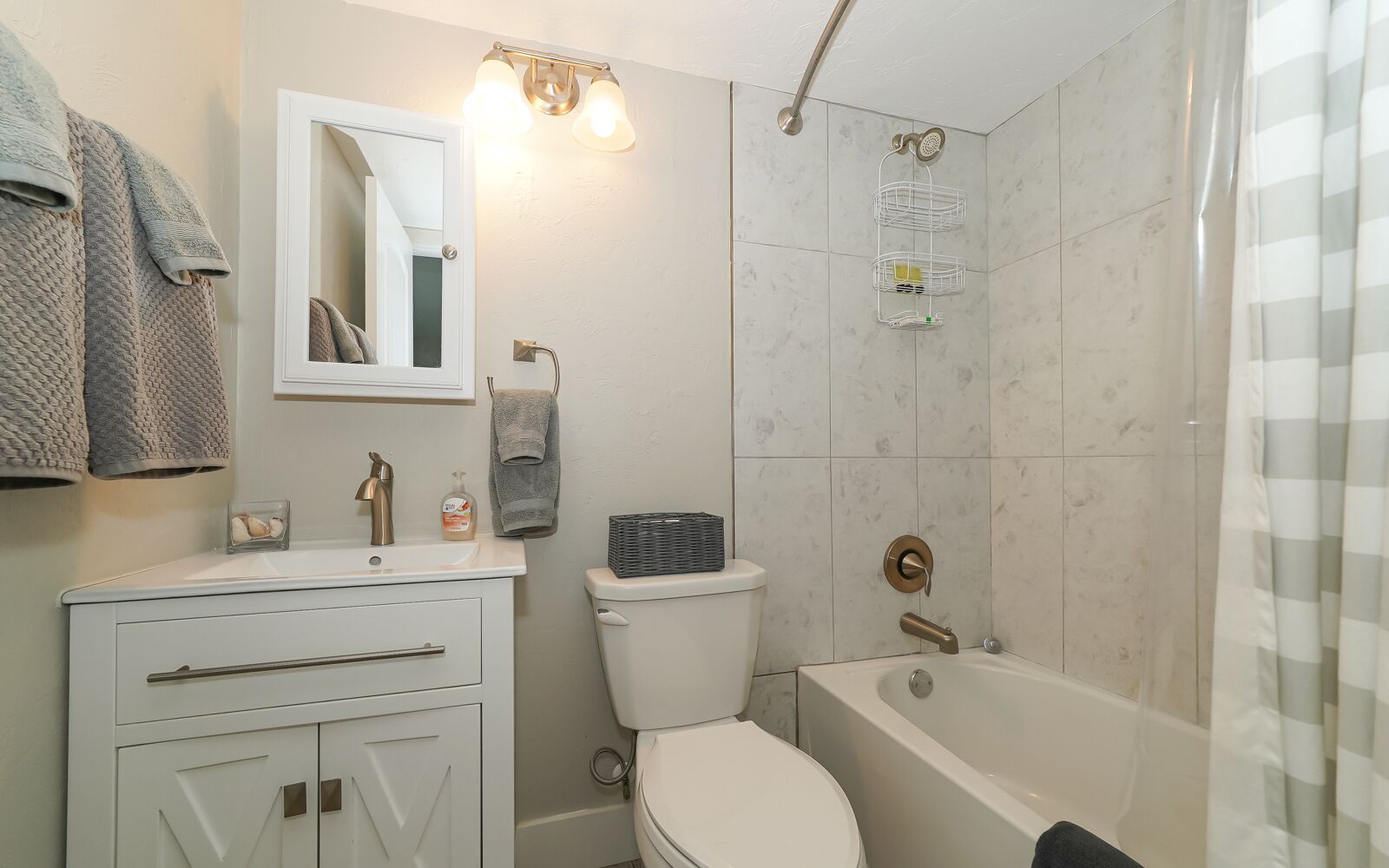 Een moderne badkamer met een wit wastafelmeubel, toilet, bad en douche.