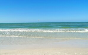A beach with clear blue water and a sandy shore.