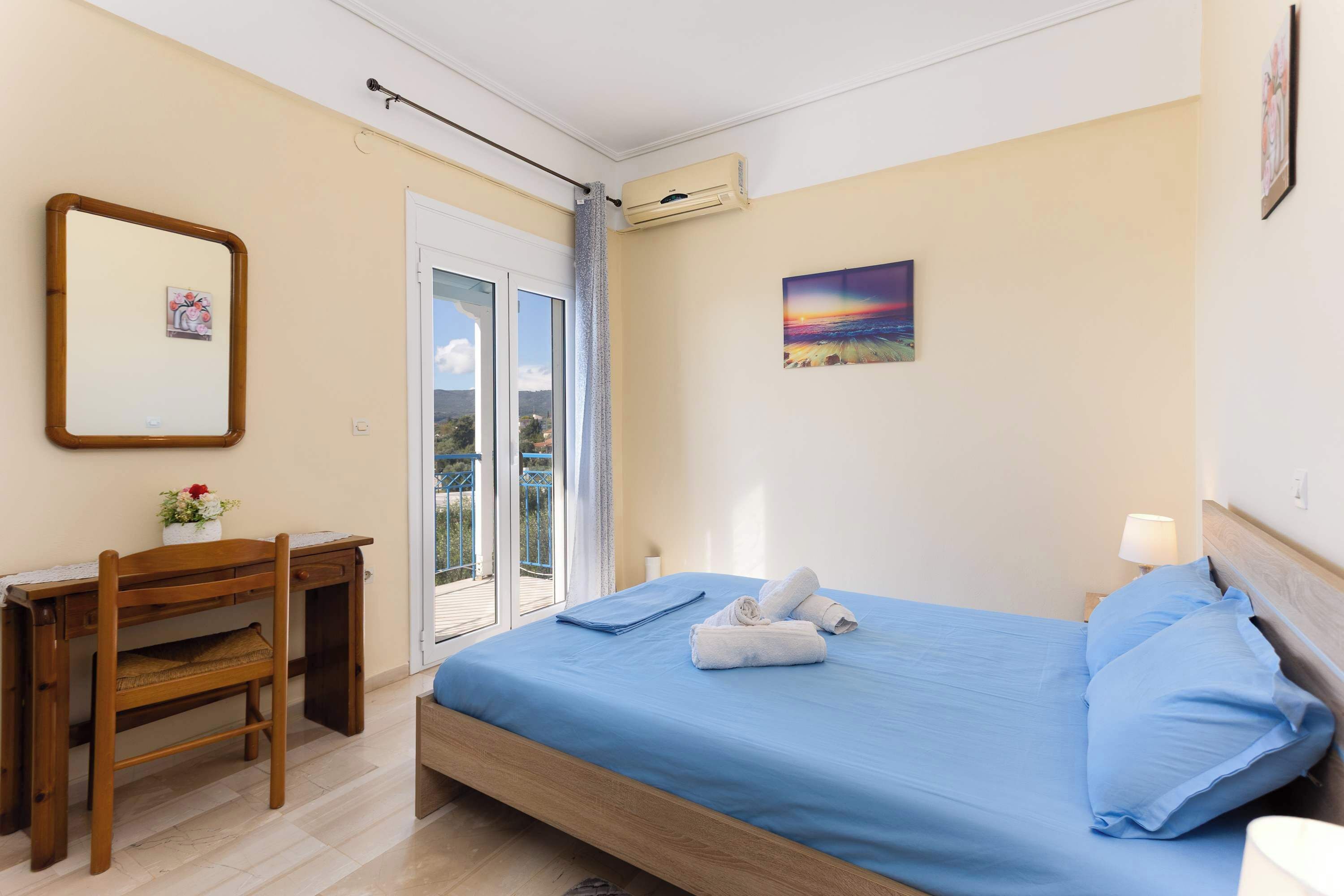 A bedroom with a bed, a desk, a chair, a picture frame, and a window.