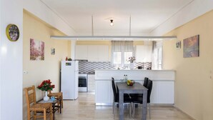 Una cocina moderna con armarios blancos, una isla central y un comedor con mesa y sillas.