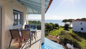 Un balcón con mesa y sillas, con vista a un paisaje costero que ofrece una vista despejada del mar y la vegetación.