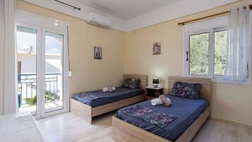 Een slaapkamer met twee eenpersoonsbedden, een klein nachtkastje met een lamp en een raam met gordijnen.