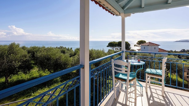 Un balcón con vistas al mar, una mesa con sillas y una barandilla.