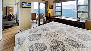 Een slaapkamer met een groot bed, een bureau en uitzicht op zee.