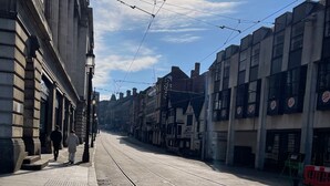 Une voie ferrée de tramway bordée de bâtiments des deux côtés, dont un restaurant Burger King.