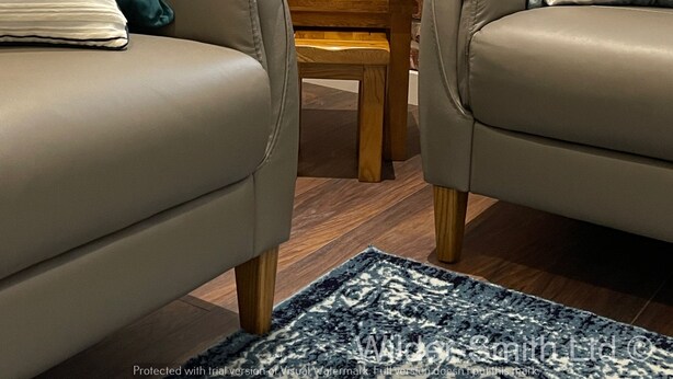 Un salon avec deux fauteuils en cuir, une petite table en bois et un mur en briques.