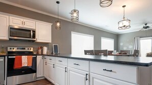 A modern kitchen with white cabinets, stainless steel appliances, and pendant lighting. - 51-05 Lake view unit Close to SDC Indoor/Outdoor pools (Branson)