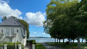 A residential street with a house, a fire hydrant, and a pedestrian path leading to a body of water. - Vacation apartment Villa am Meer - Experience Stralsund (Stralsund)