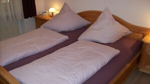 A double bed with two pillows and a nightstand with a lamp.