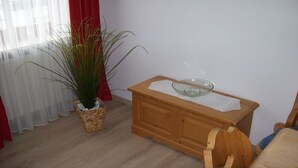A room with a wooden side table, a glass bowl, a potted plant, and a chair.