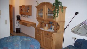 A room with a wooden cabinet, a blue patterned sofa, and a small table with a plant.