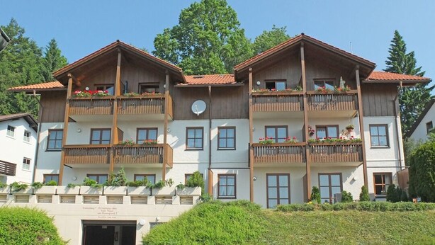 A multi-story hotel with wooden balconies, a central entrance, and a landscaped garden area. - Comfort apartment Schönblick for 5 pers. with great view & view of the Silberberg (Bodenmais)