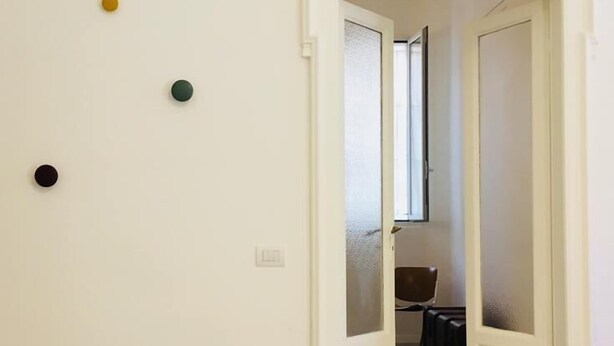 Un pasillo con una puerta que da a una habitación. Hay cuatro pequeños puntos de colores en la pared.