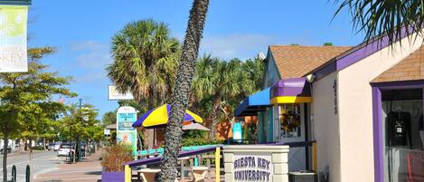 A university building with a sign reading "Siesta Key University" and a beachside location.