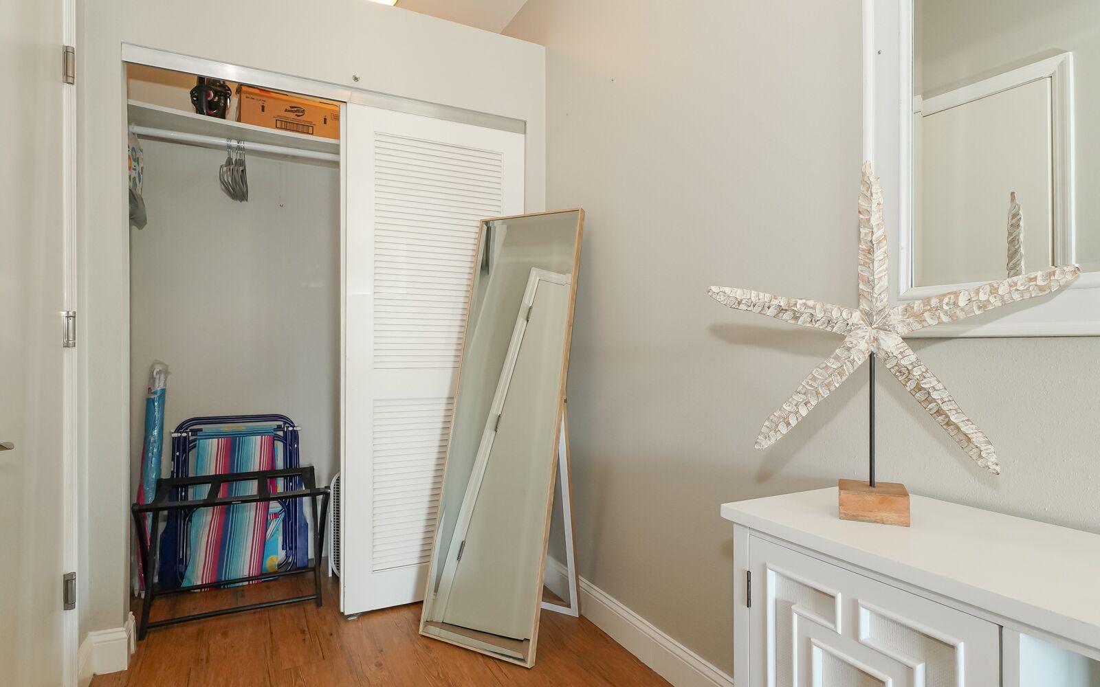 A room with a closet, a large mirror, and a starfish decoration.