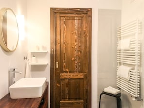 A bathroom with a wooden door, a white sink, a mirror, and a towel rack. - Flatty La Thuile - Little Fish (La Thuile)