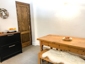 A wooden dining table with a white fluffy rug and a bowl of eggs. A black dresser with gold handles is to the left. - Flatty La Thuile - Little Fish (La Thuile)