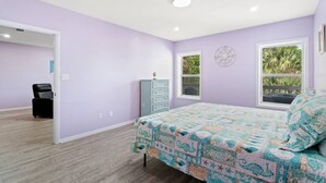 Une chambre à coucher comprenant un lit, une commode, une chaise et une fenêtre donnant sur un paysage verdoyant.