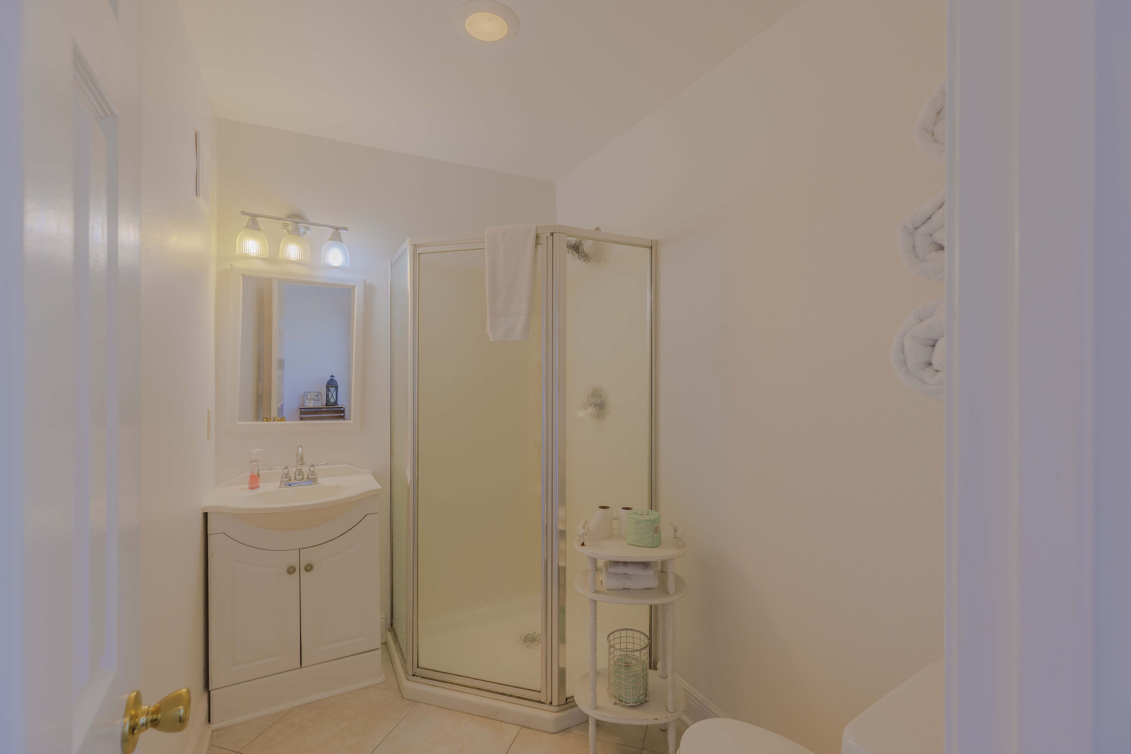 Un bagno con doccia vetrata, lavabo con specchio e servizi igienici.