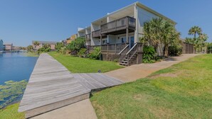 A modern multi-story building with balconies, a wooden deck, and a pool. - Cozy Coastal Beach Villa (Pensacola Beach)