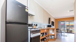 A modern kitchen with a stainless steel refrigerator, a stove, and wooden cabinets.