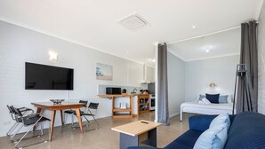 A modern, compact living space with a kitchenette, a dining area, a sofa, and a bed. - Windsurfer Beach Chalet  2 - No Frills holiday vibe (Lancelin)