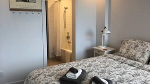 A hotel room with a bed, a nightstand, a lamp, and a shower area. - Huge terrace - Downtown condo - Free parking - Near Old Port (Montréal)