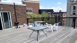 A wooden deck with a table and chairs, a grill, and a sliding glass door. - Huge terrace - Downtown condo - Free parking - Near Old Port (Montréal)