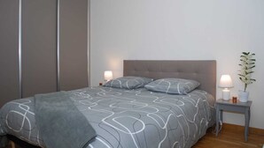 A bedroom with a bed, bedside tables, and a potted plant. - Appartement T3 Avec Terrasse et Accès Direct à la Plage (Fréhel)