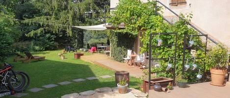 Een terras met een houten terras, tuinmeubels en potplanten.