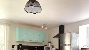 Una cocina moderna con armarios color turquesa, un refrigerador de acero inoxidable y una mesa de comedor de madera con sillas.