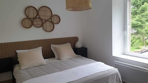Un dormitorio con cama, almohadas, cabecera, ventana y adornos en la pared.