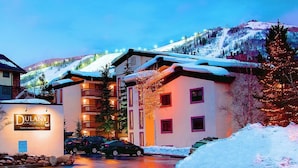 A hotel with a snow-covered roof, multiple balconies, and a view of a snowy mountain. - Dulany 302 - Heart of Base Area, Ideal for Couples, Hot Tub, WD (Steamboat Springs)