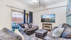 Una sala de estar con sofás de cuero, un televisor y un cuadro con vista a la ciudad.
