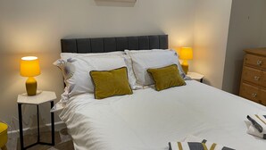 A neatly made bed with white bedding and two green pillows, flanked by two bedside tables with yellow lamps. - Central Nottingham Gem - Luxurious 2-bed Apartment (Nottingham)
