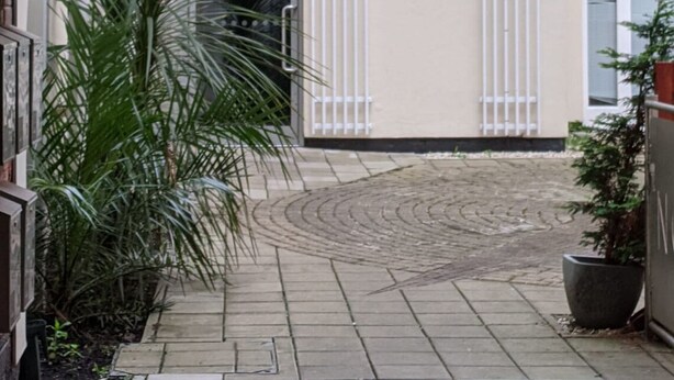 A paved courtyard with a palm tree, a metal gate, and a building facade. - Central Nottingham Gem - Luxurious 2-bed Apartment (Nottingham)