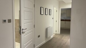 A hallway with white walls, a radiator, and framed pictures. - Central Nottingham Gem - Luxurious 2-bed Apartment (Nottingham)